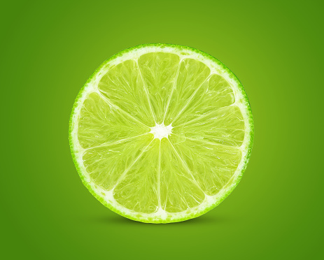 Slice of fresh lime fruit isolated on green background