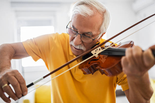 hombre mayor tocando el violín en casa - musical instrument violin sheet music music fotografías e imágenes de stock