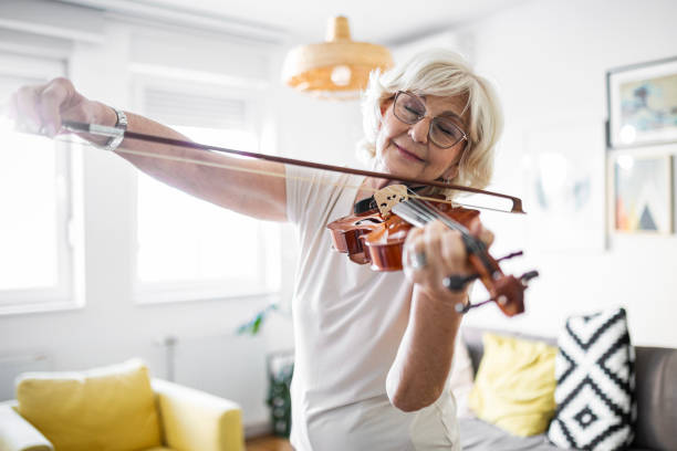 senior woman enjoying playing violin at home - violin family imagens e fotografias de stock