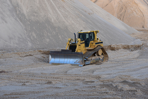road leveling heavy equipment in a gravel quarry on an off-road surface on a sunny autumn day