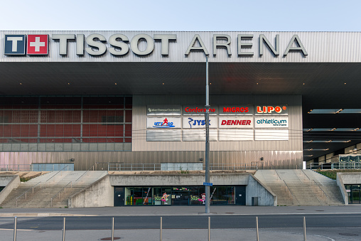 Exterior view of the stadium building with a view of the Tissot Arena lettering on the roof of the stadium. The ice hockey club EHC Biel and the football club FC Biel-Bienne 1896 plays in the Tissot Arena. The building also houses the Shopping Les Stades shopping centre. 08/28/2022 - Boulevard des Sports 18, 2504 Biel Bienne, canton Bern, Switzerland