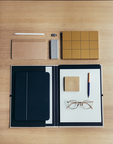 Notebooks, glasses, a tablet and a pen on an office desk.