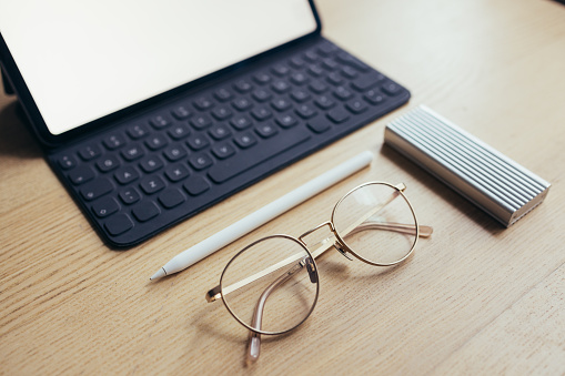 Business essentials: a tablet, a pair of glasses and a hard disk in close up.