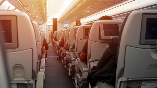 Interior of an airplane with passengers sitting on seats. Selective Focus