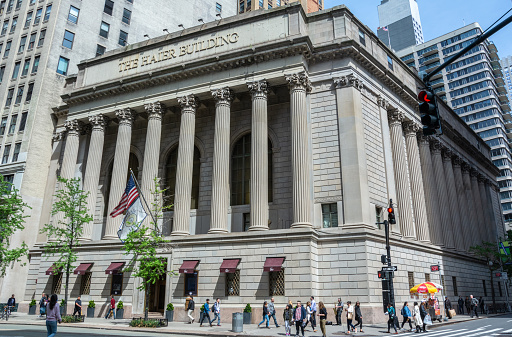 New York City, United States of America - May 4, 2017. The Haier Building, also known as Greenwich Savings Bank Building, at 13521362 Broadway in the Midtown Manhattan neighborhood of New York City. Constructed as the headquarters of the Greenwich Savings Bank from 1922 to 1924, it occupies a trapezoidal parcel bounded by 36th Street to the south, Sixth Avenue to the east, and Broadway to the west. The Greenwich Savings Bank Building was designed in the Classical Revival style by York and Sawyer. The exterior, wrapping around the three sides of the building, consists of a base of rusticated stone blocks, atop which are Corinthian-style colonnades. The building was purchased by Chinese appliance company Haier in 2001 and soon afterward was renamed for Haier. Exterior view with people.