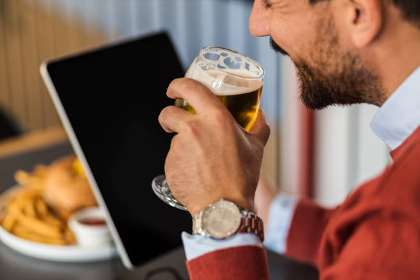 istock Closeup of a businessman drinking a beer in a restaurant while using an iPad 1435935291