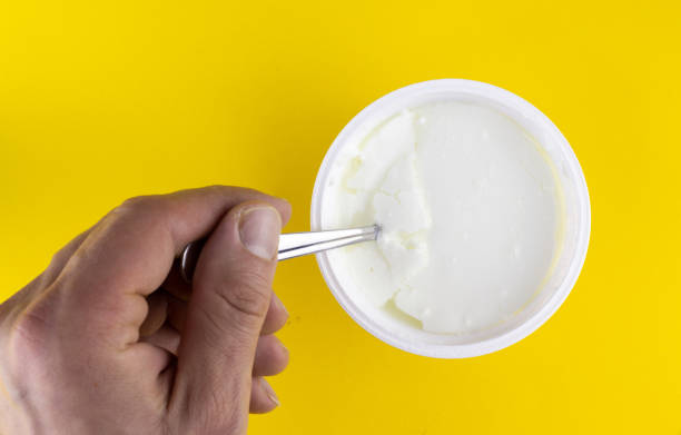 istock hand holding plastic cup with natural yogurt and spoon, isolated on color background 1435935350