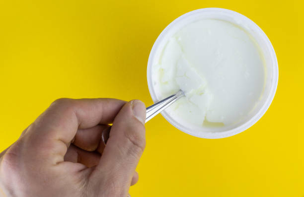 istock hand holding plastic cup with natural yogurt and spoon, isolated on color background 1435935353