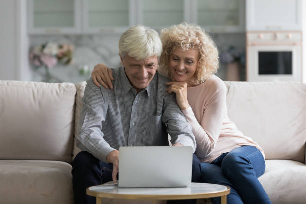 istock Happy older couple sit on couch staring at laptop screen 1435937517