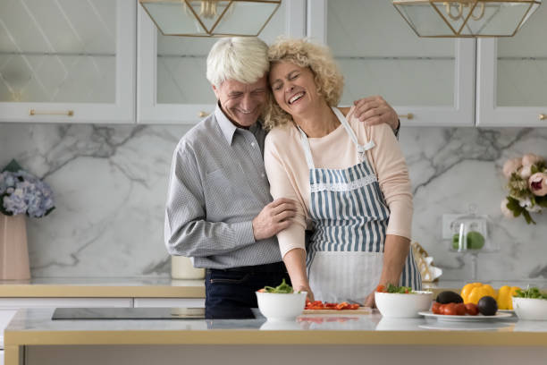 istock Happy older couple cooking and laughing in modern kitchen 1435937535