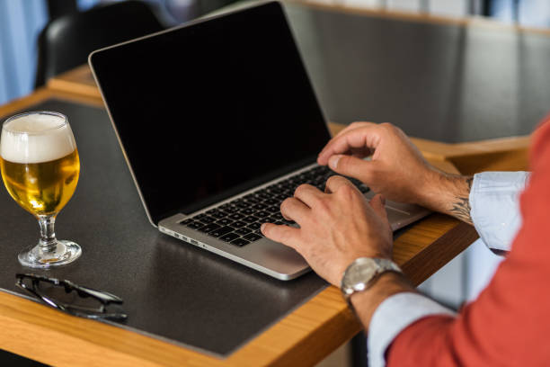 istock Businessman typing a report on a laptop while drinking a beer in a restaurant 1435938620