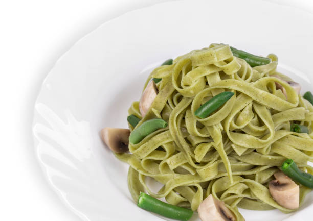 Pasta tagliatelle with beans and mushroom. Pasta tagliatelle with beans and mushroom as haute cuisine. Whole background. It is located on a white surface. Close-up. spinach pasta stock pictures, royalty-free photos & images