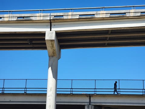 Man walking on an overpass bridge over a highway in the city of Houston