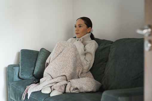 middle aged woman sitting  in room and warming herself in cold weather