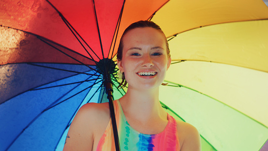 Fashion, great outfits for summer concept. Happy woman with long brown hair posing in swimsuit and colorful umbrella
