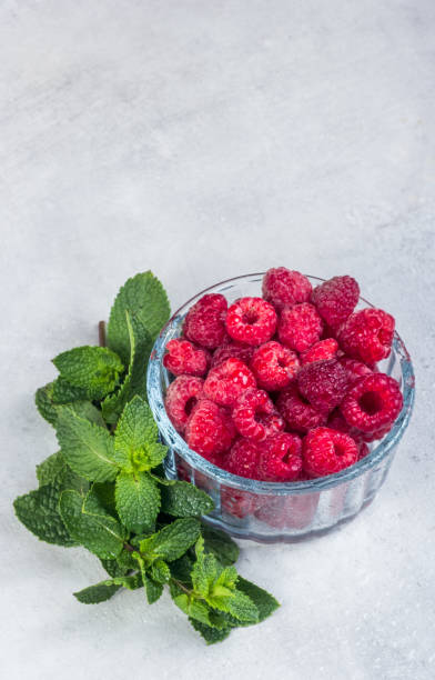 istock Bowl juicy raspberries and mint on a gray background. 1435952856