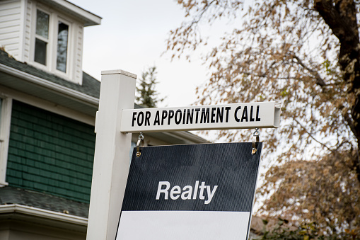A blank realty sign is in front of the house, in north america