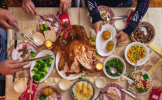 Family celebrates Christmas. At the dining table, the father carving stuffed roasted turkey and shares it with his family.