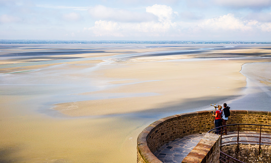 Le Mont Saint-Michel, Normandy, France - May 27 2016 : Tourist couple admiring the  scenic view from Le Mont Saint-Michel in Normandy