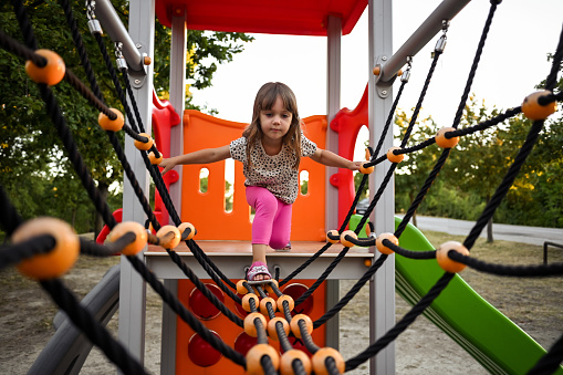 little girl climbs ropes at the playground