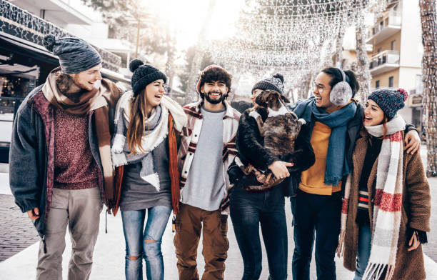 young and happy friends walk embraced in the streets of the city on a cold winter day - multiracial friends having fun during the xmas holidays outside - concept of friendship and youthful lifestyle - christmas winter sunset snow imagens e fotografias de stock