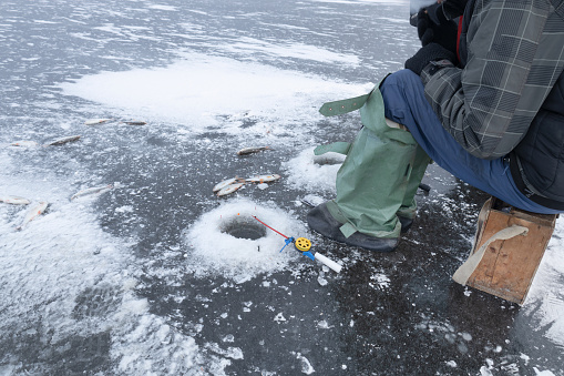 Fishing rods lie on the ice near the ice hole, winter fishing on a frozen lake