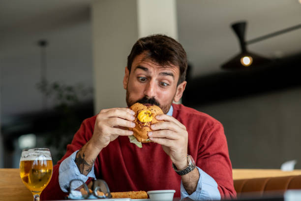 istock Attractive businessman eating a burger and drinking beer making googly eyes mimic 1435965671