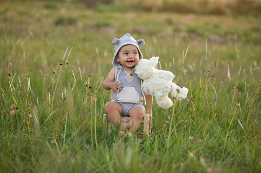 Cute one year-old latin american boy with teddy costume smiling outsoors - Sunset time - Buenos Aires Province - Argentina
