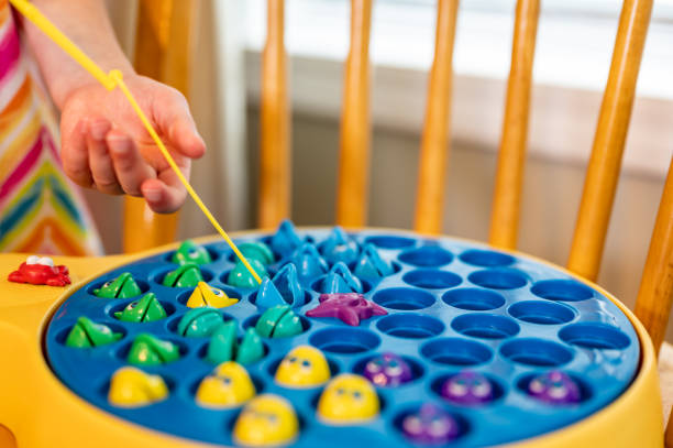 istock Children's game of using a miniature pole and line lowered into open plastic fish to catch them as the pond spins. 1435977715