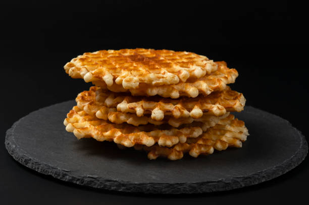 Fresh crispy Belgian waffles with a golden crust on a black stone plate on a black background Fresh crispy Belgian waffles with a golden crust on a black stone plate on a black background deli pie stock pictures, royalty-free photos & images