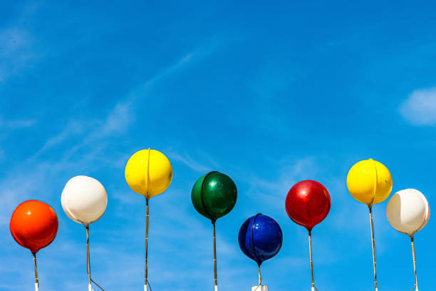 Little boy of African descent releasing an orange balloon into the sky.