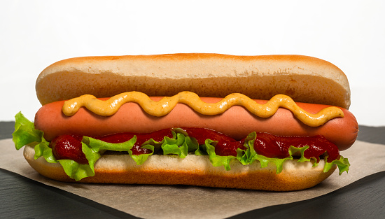 Freshly cooked hot dog lies on parchment paper before serving