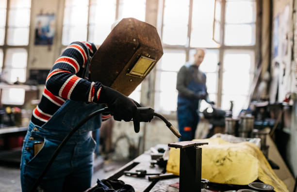 Two construction workers are welding large iron for the building foundation.