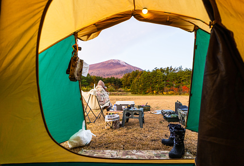 Looking out through tent door to camp and Mt. Iwate in the background with Autumn colored trees.