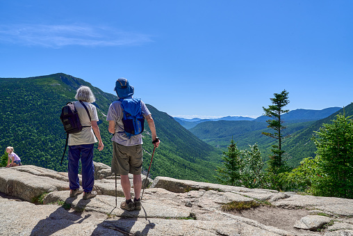 Hart's Location, NH USA - August 3, 2022: Hikers looking at the scenic view of Crawford Notch from Mt. Willard, (2,865 ft) in Carroll County in the White Mountains of NH on a summer day with a clear blue sky