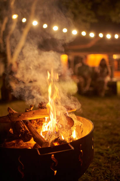 istock Bonfire burning in a garden a summer night, unknown people in the background. 1435995238