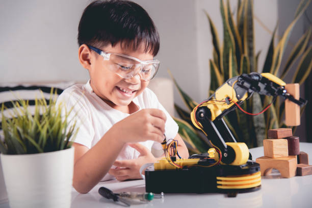 istock Happy Asian little kid boy using screwdriver to fixes screws robotic machine arm in home workshop 1435996330