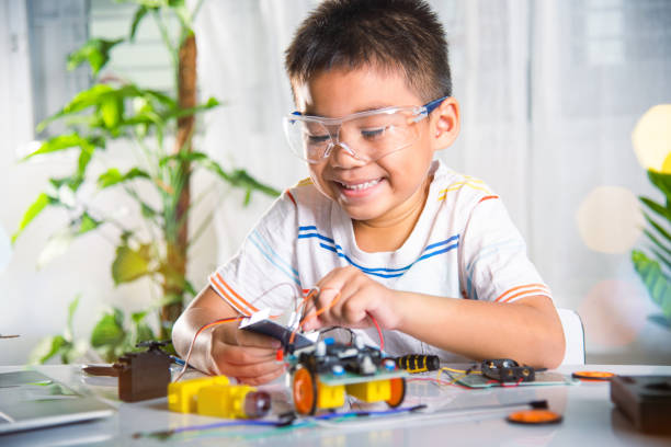 istock Asian kid boy plugging energy and signal cable to sensor chip with open-source hardware and software robot car 1435996394