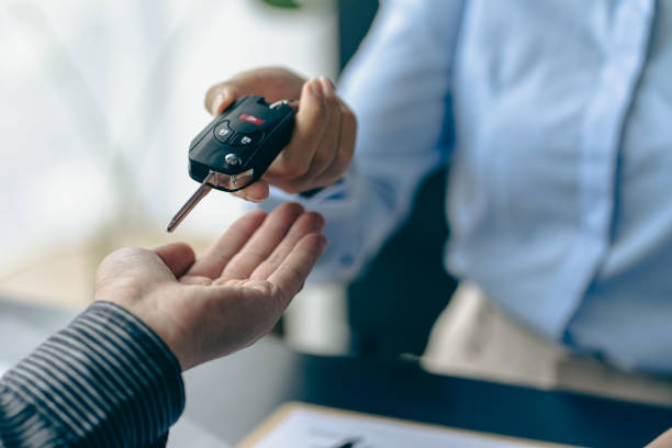 of the representative Hold the car keys to the new owner after signing the leasing contract in the car sales contract document. stock photo