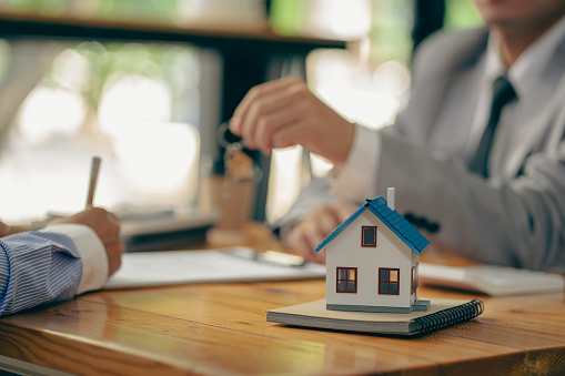 Sales representatives hand out the house keys to customers after signing a contract to buy a house or rent a new home on the table. concept of buying a house