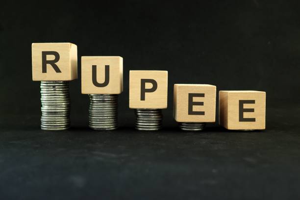 istock Indian rupee weakening, value depreciation and devaluation concept. Decreasing stack of coins on dark black background. 1436000244