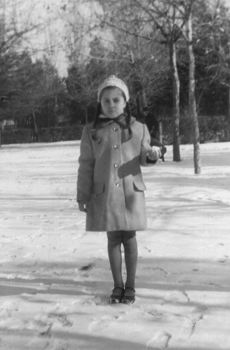 Black and white image taken in the 60s: little girl posing in the snow