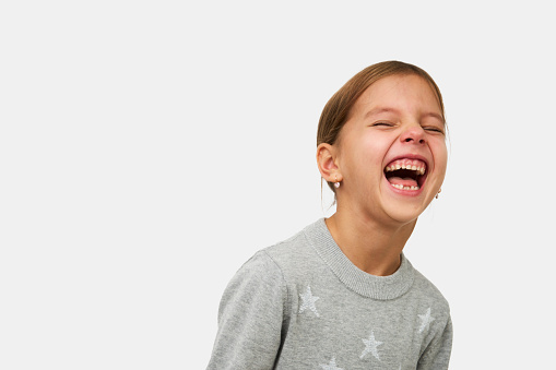 Cute little girl laughing on white background with copy space. Portrait of a smiling child girl, close-up