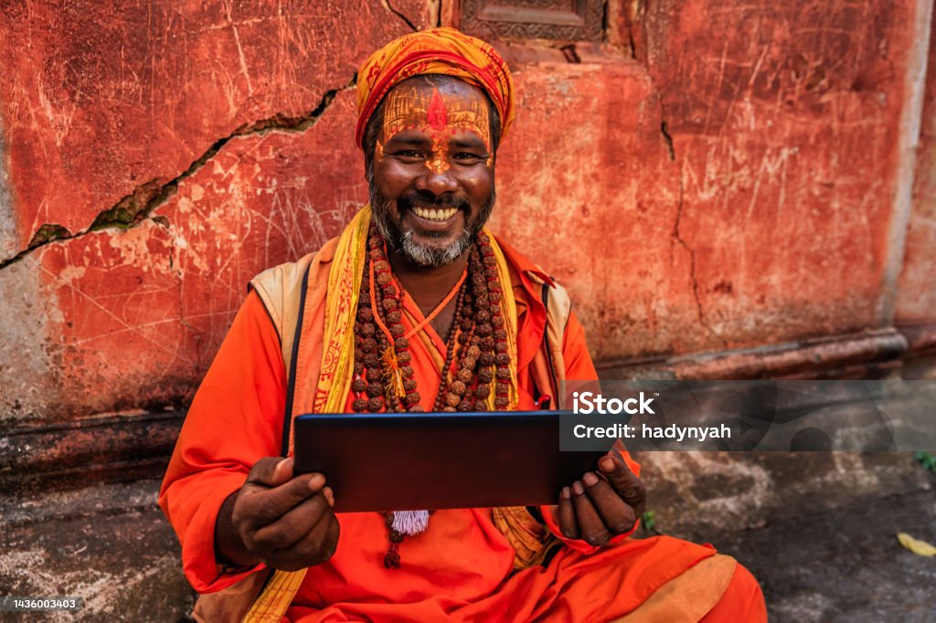 Sadhu - indian holyman using digital tablet Sadhu - indian holyman using the digital tablet. In Hinduism, sadhu, or shadhu is a common term for a mystic, an ascetic, practitioner of yoga (yogi) and/or wandering monks. The sadhu is solely dedicated to achieving the fourth and final Hindu goal of life, moksha (liberation), through meditation and contemplation of Brahman. Sadhus often wear ochre-colored clothing, symbolizing renunciation. Pashupatinath Stock Photo
