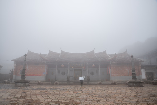 In foggy weather, the figure of a man with an umbrella in front of the temple