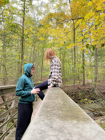 A young couple takes a moment to rest on a wooden walkway.    This wooden walkway gives hikers safety across the crevasse in the woods of Ohio. The young couple takes a moment of rest to show compassion for one another.