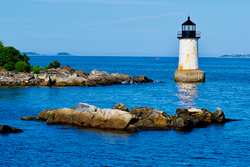 Salem, Massachusetts, USA - June 24, 2019: The Fort Pickering Lighthouse stands out in evening sunlight at the entrance to Salem Harbor on a summer evening.