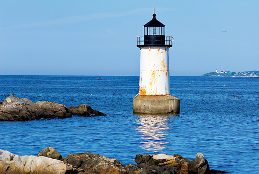 Salem, Massachusetts, USA - June 24, 2019: The Fort Pickering Lighthouse stands out in evening sunlight at the entrance to Salem Harbor on a summer evening.