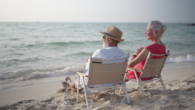 Senior couple sitting and talking at the beach.