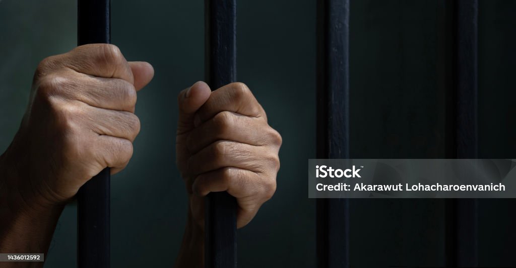 Hand of convicted prisoner behind the cell bar inside jail for incarceration, criminal and limited freedom concept Hand of convicted prisoner behind the cell bar inside jail for incarceration, criminal and limited freedom Prison Stock Photo